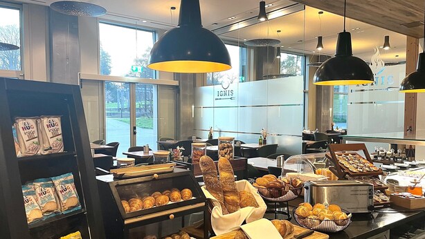 Mostrador de panadería con diversos productos horneados y una estación de café.