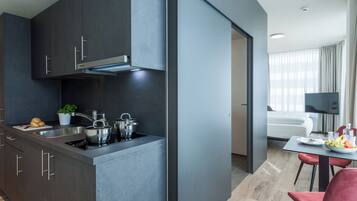 A modern kitchen with dark cabinetry, a built-in stove, and a dining area with a table and chairs.