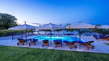 Una piscina al aire libre de temporada, sombrillas