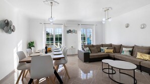 Un salon moderne comprenant un coin repas, un ensemble de canapés et une table basse.