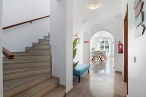 Un escalier menant à une salle à manger équipée d’un banc, d’un extincteur et d’un mur orné de panneaux indicateurs.