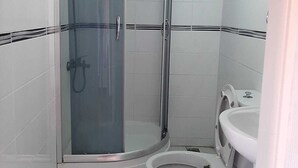 A small, enclosed shower area with a glass door and a toilet. - Kural Pansiyon (Ayvalik)