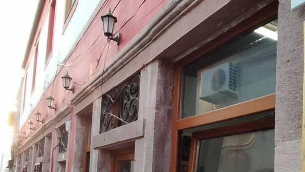 A row of buildings with large windows and a red awning. - Kural Pansiyon (Ayvalik)