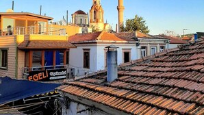 A coastal town with a prominent mosque, a church, and a building with a sign reading "Gayrimenkul". - Kural Pansiyon (Ayvalik)
