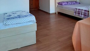 A room with a bed, a small table, and a wooden wardrobe. - Kural Pansiyon (Ayvalik)