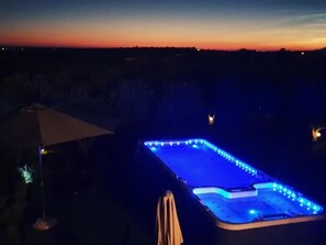 A heated outdoor swimming pool with blue LED lights at dusk.