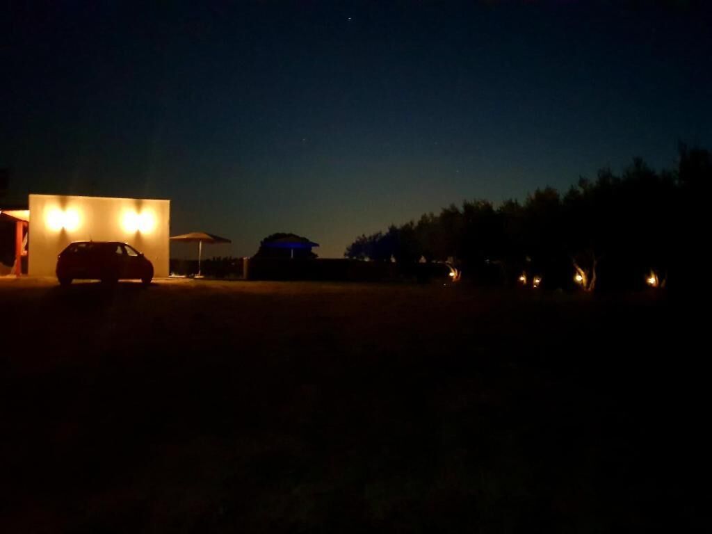 Nachtszene mit einem geparkten Auto vor einem Gebäude mit beleuchteten Fenstern.