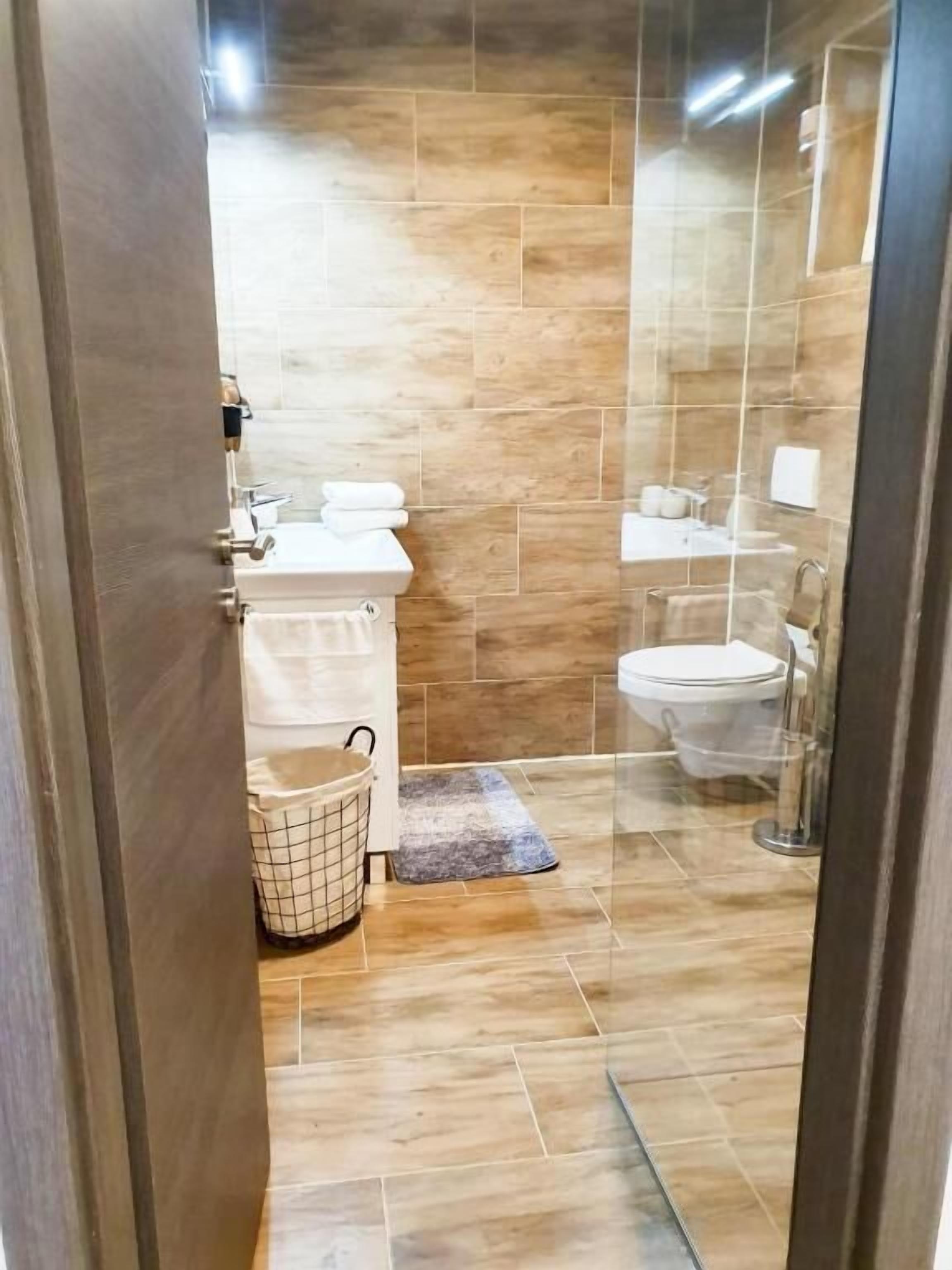 Une salle de bain moderne avec un plancher en bois, un lavabo, des toilettes et un espace douche.