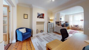 A living room with a blue sofa, a wooden coffee table, a fireplace, and a television. - Princes Street | Oxford Holiday Let | 3 Beds & Sleeps 6 (Oxford)
