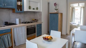 Une cuisine compacte avec des meubles bleus, un plan de travail blanc et un coin repas comprenant une table et des chaises.