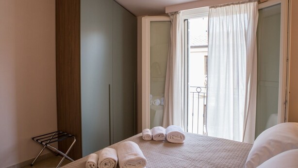 Une chambre avec un lit, une armoire, un étendoir et une vue sur le balcon.