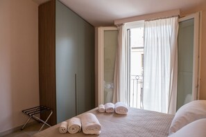 Une chambre avec un lit, une armoire, un étendoir et une vue sur le balcon.