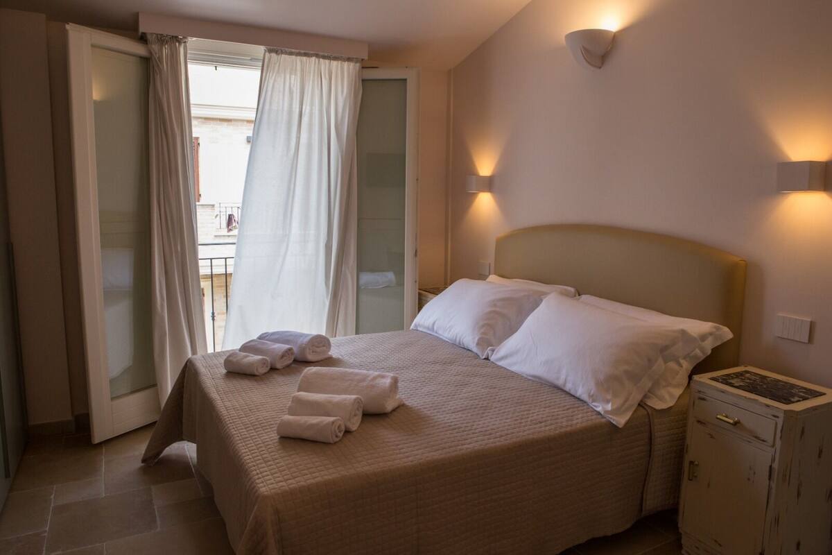 Una habitación de hotel con una cama, dos almohadas, una mesita de noche y un armario.