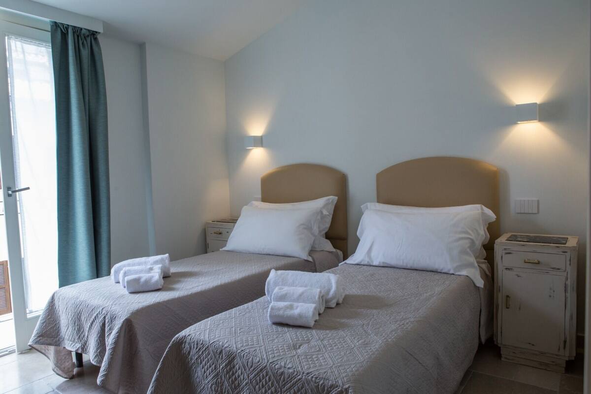 Habitación de hotel con dos camas, cada una con cabecero, mesitas de noche y lámparas.