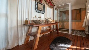 A wooden vanity with a stone basin, a mirror, and a small shelf with toiletries. - Ohorongo Tented Camp (Kamanjab)