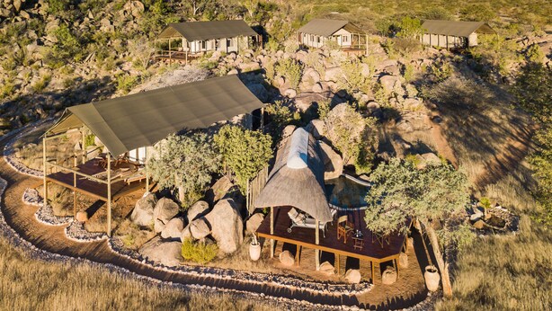 A resort with multiple cabins, a central building with a large patio, and surrounding natural landscape. - Ohorongo Tented Camp (Kamanjab)