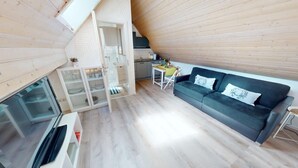 A cozy, modern living space with a loft bedroom, a dining area, and a kitchen.