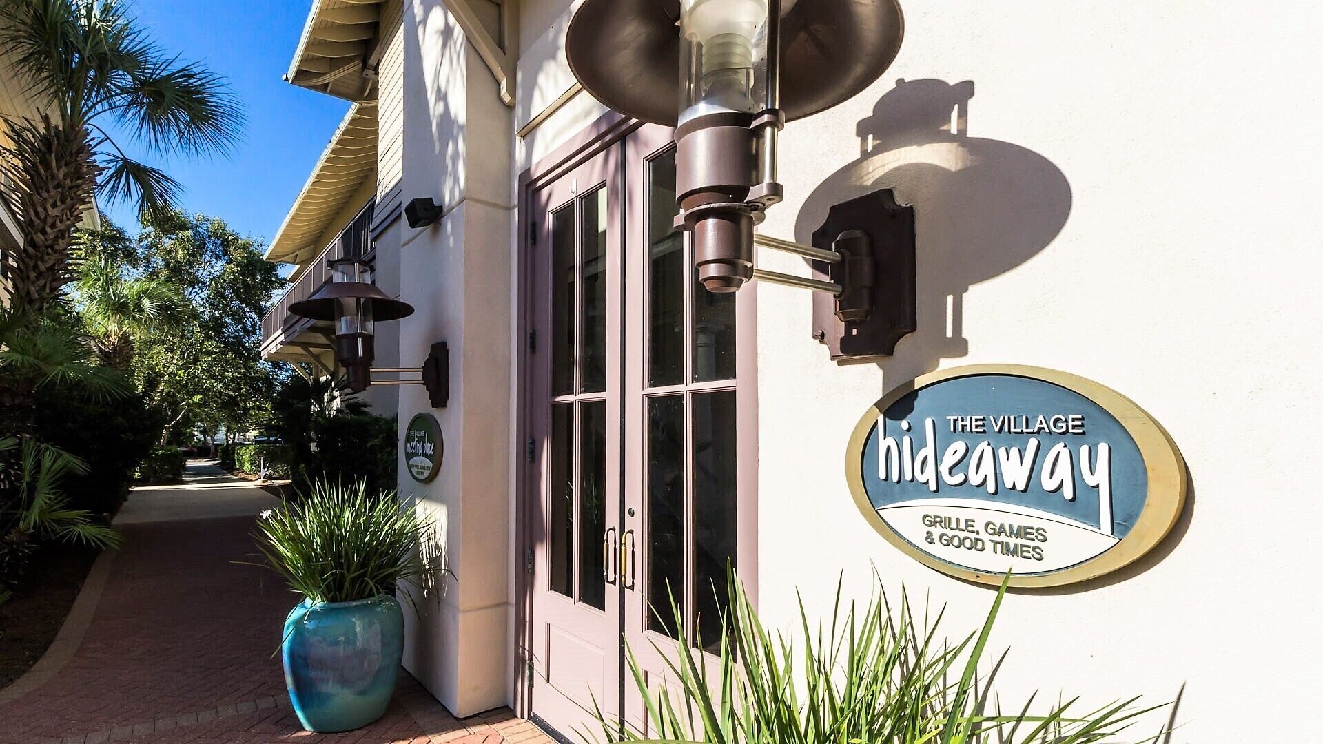 A building with a sign that reads "The Village Hideaway" and mentions "Grille, Games & Good Times".