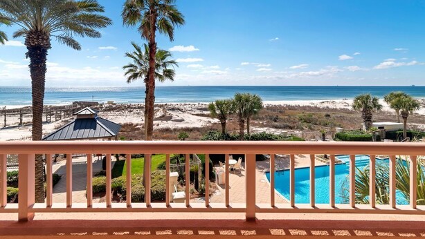 Ein Balkon mit Blick auf Strand und Meer, ein Pool und Palmen.