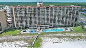 Un hotel di grandi dimensioni con numerosi balconi, una piscina e una spiaggia.