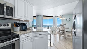 Una cucina moderna con mobili bianchi, elettrodomestici in acciaio inossidabile, un piano di lavoro in granito e un'area pranzo con vista.