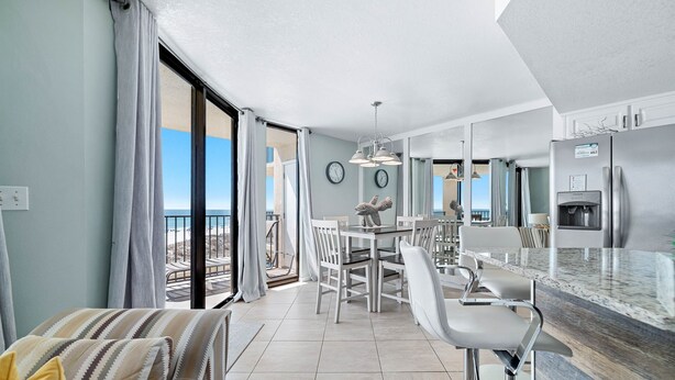 Una cucina moderna con frigorifero integrato, zona pranzo con tavolo e sedie, e un balcone con vista.