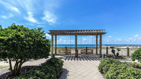 Een houten pergola met uitzicht op het strand en de oceaan.