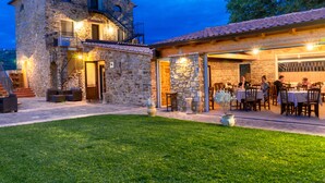 A stone building with a balcony, a covered patio with tables and chairs, and a grassy lawn. - Le Querce Farmhouse (Agropoli)