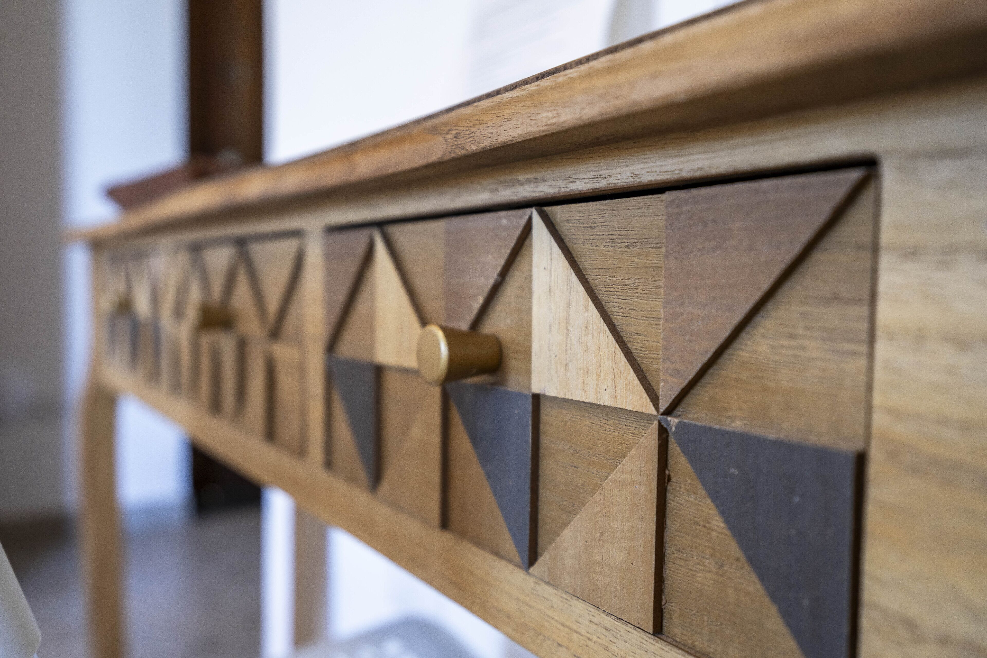 Primer plano de una mesa de madera con patrones geométricos y un pomo central.