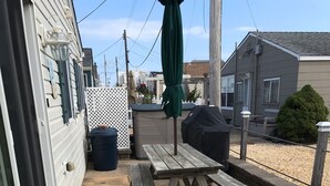 Un patio con mesa de picnic de madera y bancos, una parrilla y un área cubierta para la barbacoa.