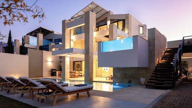 Una casa moderna de varios pisos con piscina, mobiliario de exterior y una escalera.