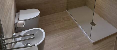 A modern bathroom with a toilet, a glass shower enclosure, and a window with a view of a pool.