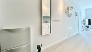 Een moderne, minimalistische kamer met een grote spiegel, inbouwmeubels en een cactus.