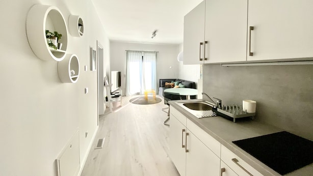 Een moderne keuken met witte kastjes, een zwart aanrecht en een spoelbak.