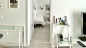 Een hotelkamer met een bed, een bureau, een televisie en een plank met boeken en een plant.