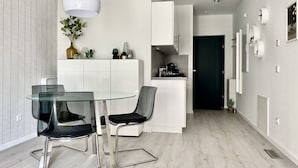 Een moderne keuken met witte kasten, een glazen eettafel en zwarte stoelen.
