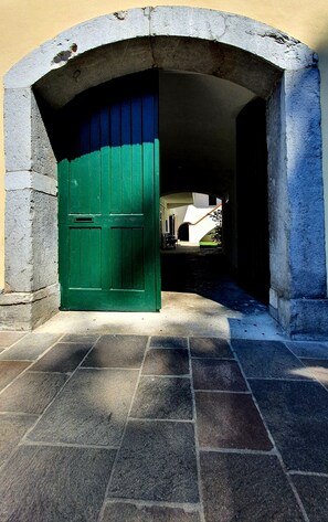 Enter through the stone archway into a charming building with a green door and a white facade.