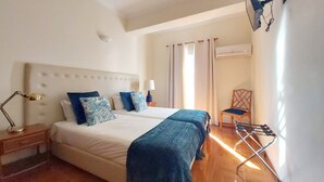 Een tweepersoonsbed met hoofdeinde, een bedlampje, een stoel en een airconditioning.