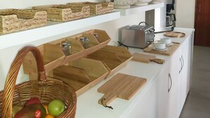 Een keuken met witte kastjes, een koffieapparaat en een fruitmand.