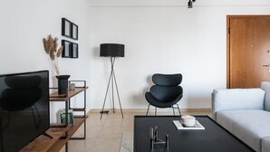 A modern living room with a TV, black chairs, a coffee table, and a bookshelf. - Superb & Comfy 2 BD Apartment in Marousi (Marousi)