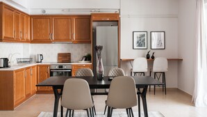 A modern kitchen with wooden cabinets, a dining table with chairs, and a refrigerator. - Superb & Comfy 2 BD Apartment in Marousi (Marousi)