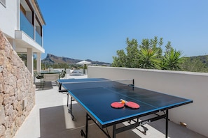 An outdoor table tennis table with two red paddles, a white umbrella, and a view of a mountain range. - Exclusive Casa Mir located in 'el Vila' with Pool & with all amenities (Puerto Pollensa)