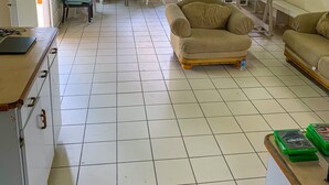 A spacious living area with a tiled floor, a dining table with chairs, and a sofa.