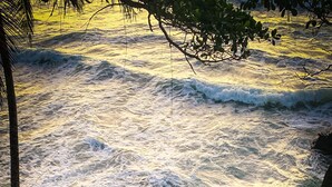 A concrete staircase leading down to a rocky shoreline with waves crashing below.