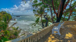 A beach with a concrete railing, a white chair, and a view of the ocean.