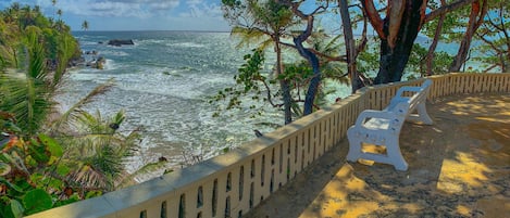 Una playa con barandilla de hormigón, una silla blanca y vista al océano.