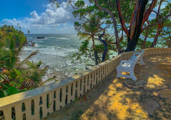 A beach with a concrete railing, a white chair, and a view of the ocean.