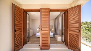 A hotel room with a large sliding wooden door, a bed, a sitting area, and a view of the outdoors. - Villa Elea, New Deluxe Golf Villa in Aphrodite Hills - 6 Bedrooms, 7 Bathrooms.  (Kouklia)