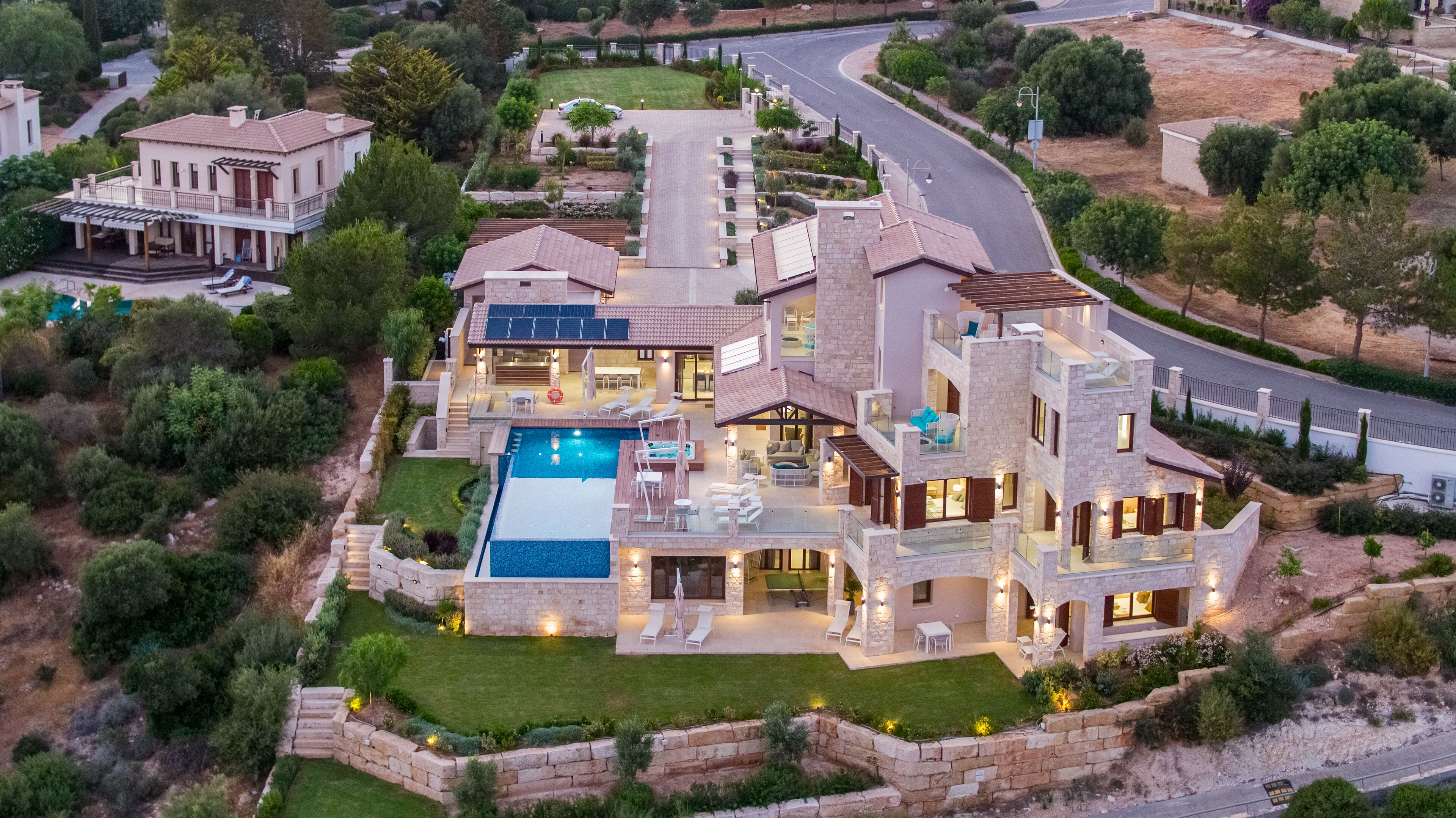 A large, multi-story house with a swimming pool, multiple balconies, and a well-maintained garden.