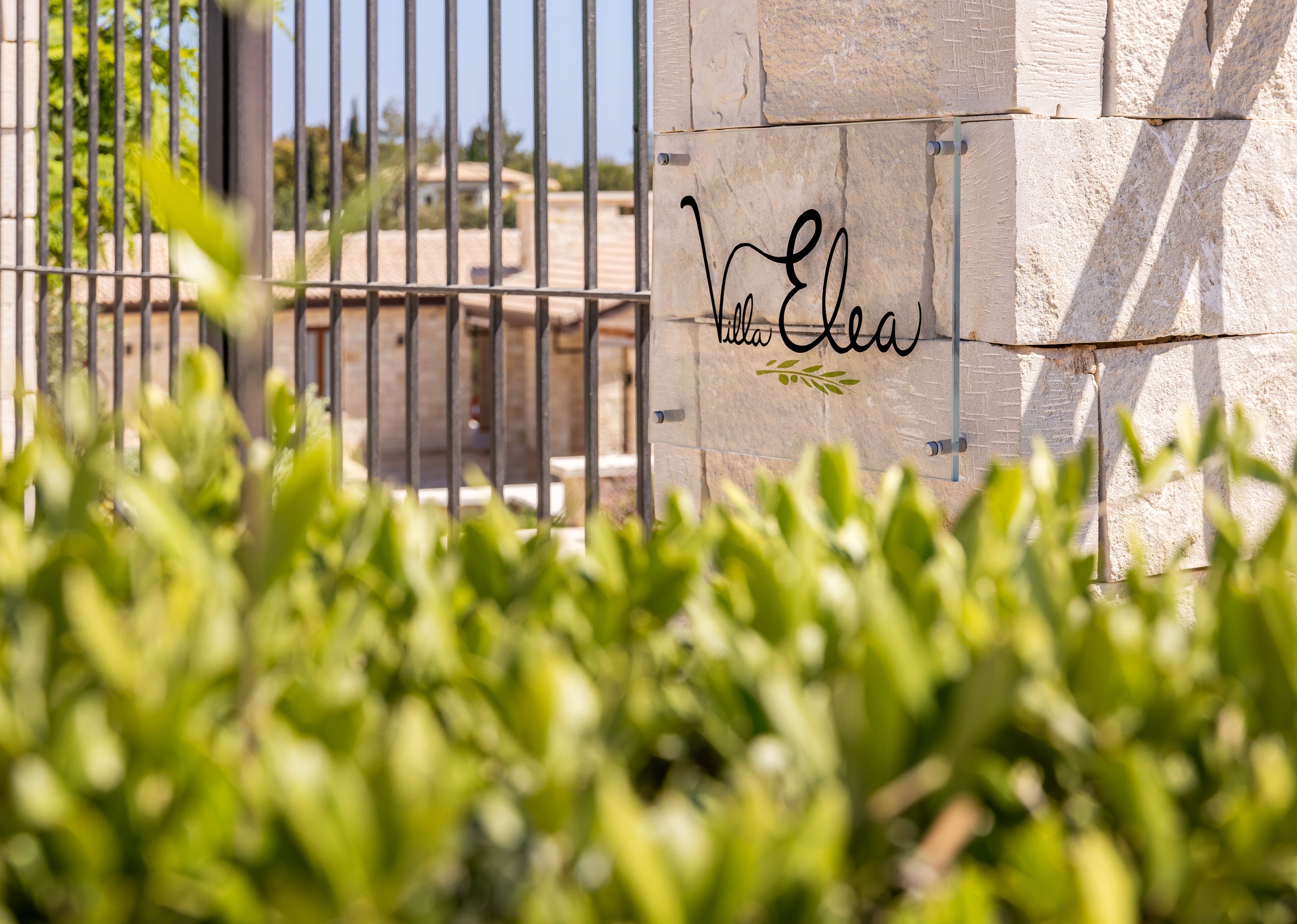 A stone wall with a metal gate and a sign that reads "Villa Elean."